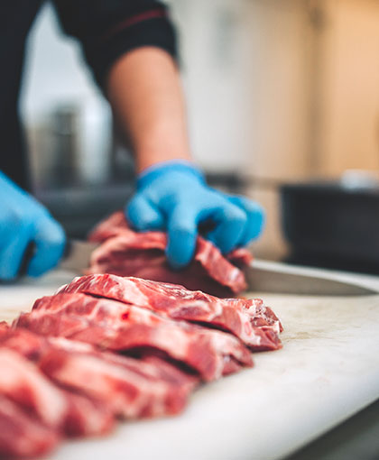 Chef cutting pieces of raw steak